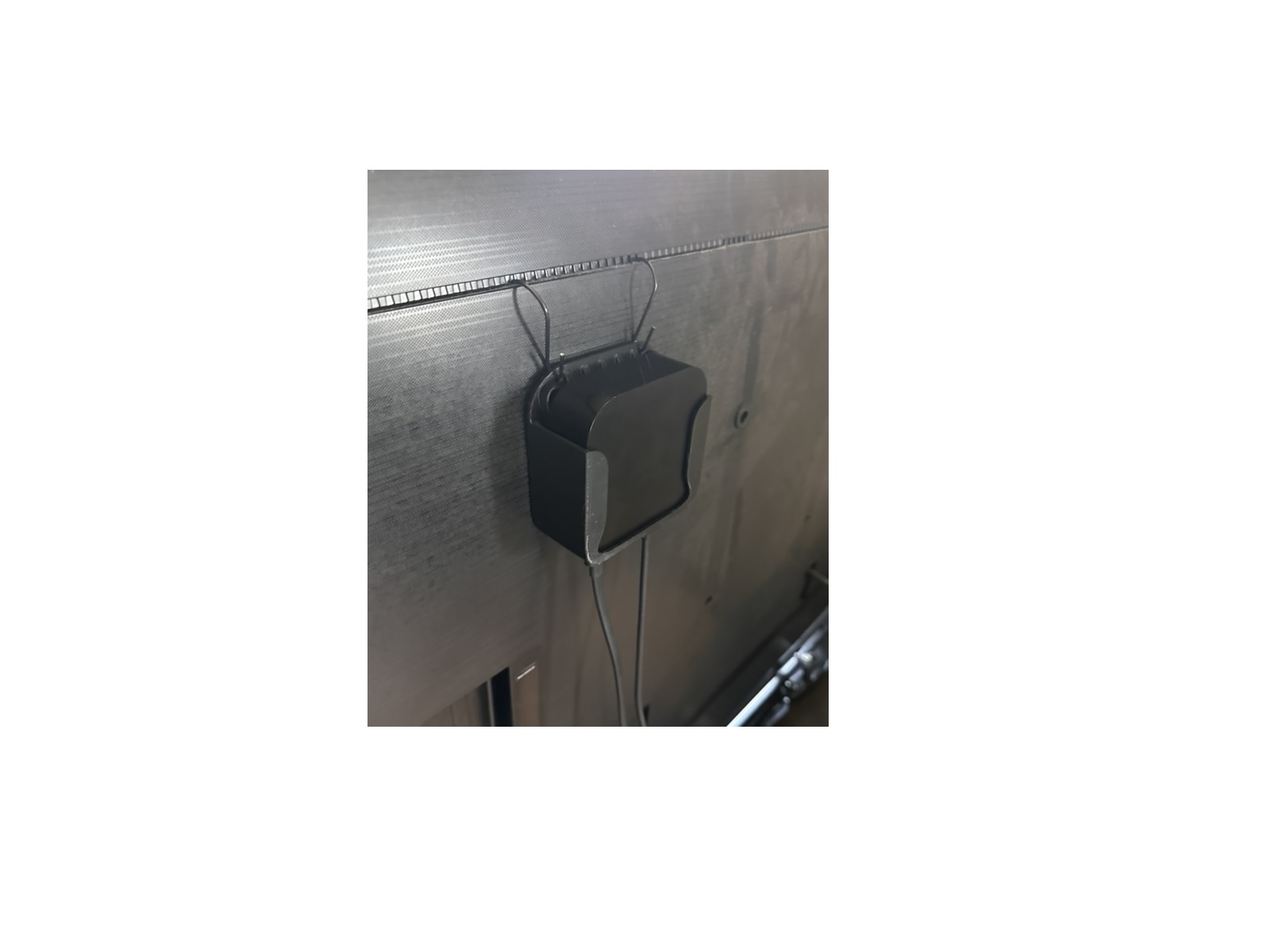 Apple TV installed behind a television using the included metal vent hooks